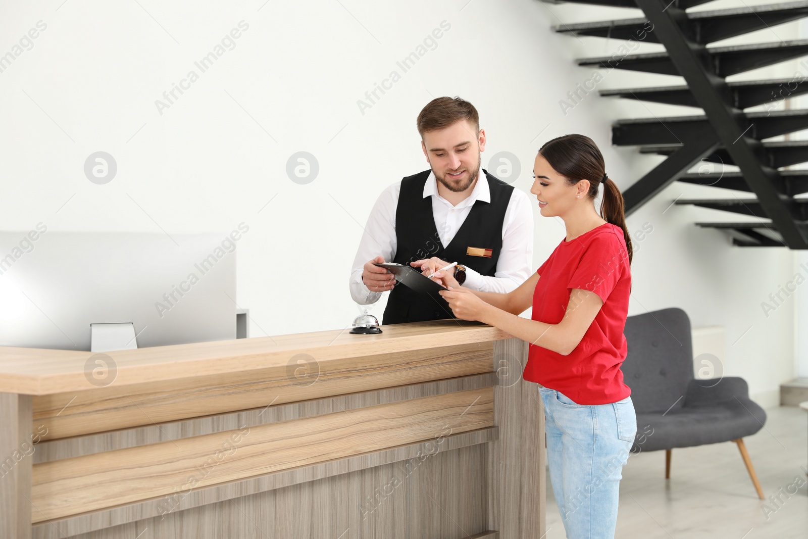 Photo of Professional receptionist working with client at desk in modern hotel