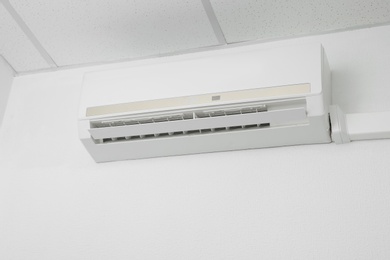 Modern air conditioner on white wall indoors