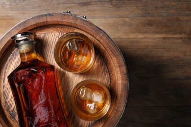 Photo of Barrel, bottle and glasses of tasty whiskey on wooden table, top view. Space for text