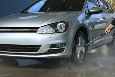 Photo of Man washing auto with high pressure water jet at outdoor car wash, closeup
