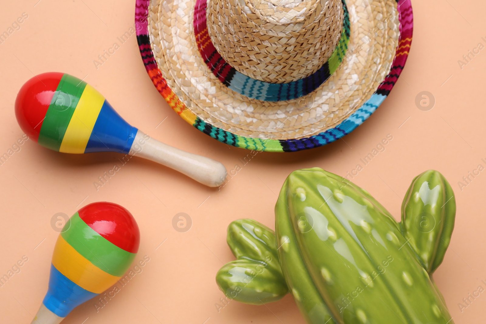 Photo of Colorful maracas, toy cactus and sombrero hat on beige background, flat lay. Musical instrument