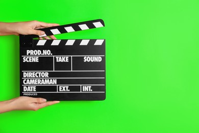 Second assistant camera holding clapper board against chroma key background, closeup. Space for text