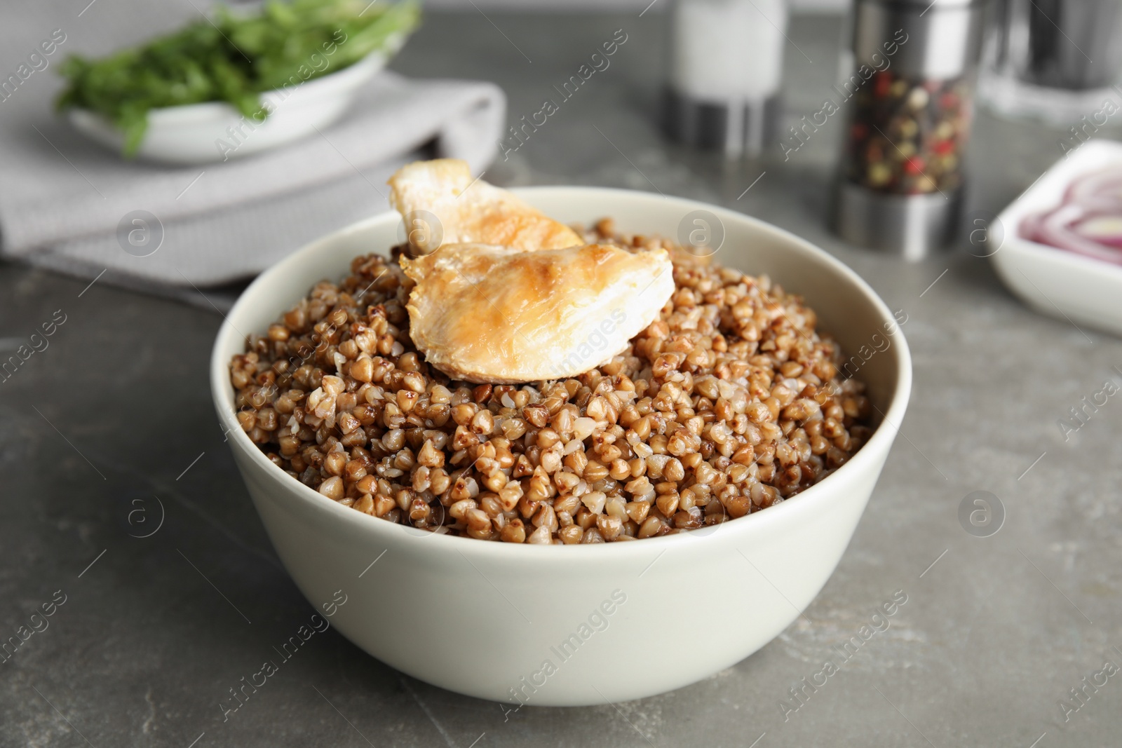 Photo of Tasty buckwheat porridge with meat on grey table