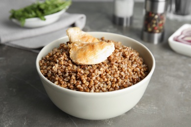 Photo of Tasty buckwheat porridge with meat on grey table