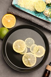 Flat lay composition with essential oil and lemons on grey table. Aromatherapy treatment