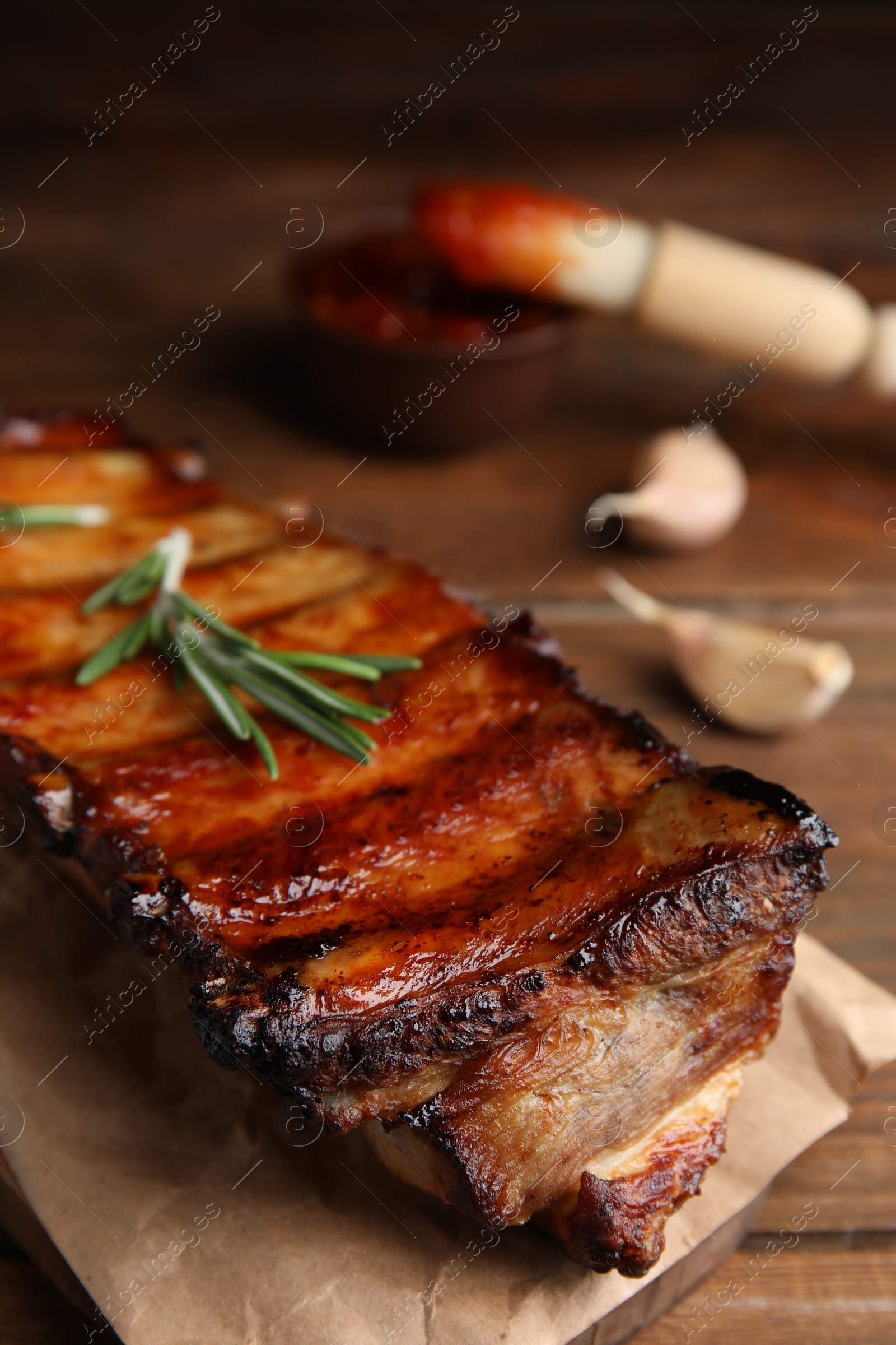 Photo of Tasty grilled ribs with rosemary on wooden table, closeup