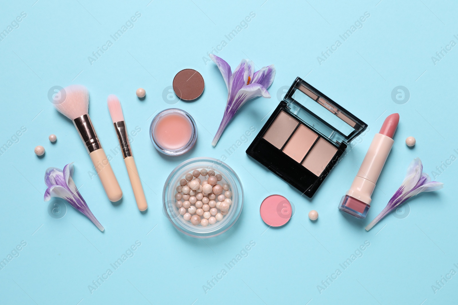 Photo of Flat lay composition with different makeup products and beautiful flowers on light blue background