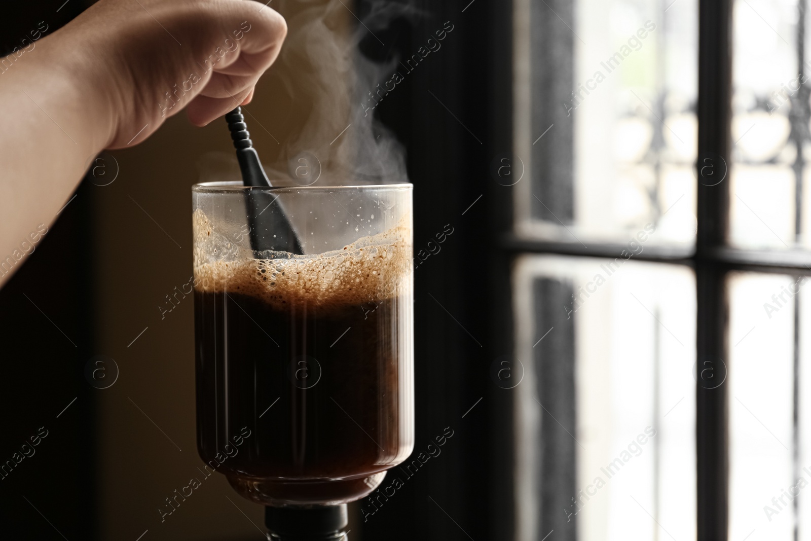 Photo of Barista brewing coffee with vacuum maker in cafe, closeup. Space for text