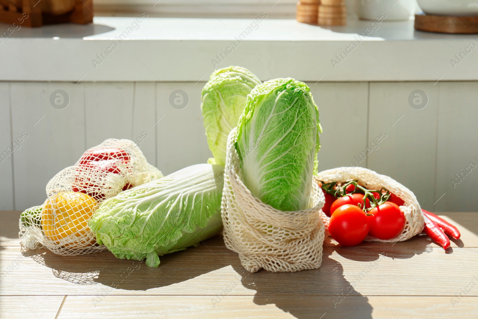 Photo of Fresh Chinese cabbages and other vegetables on light wooden table indoors