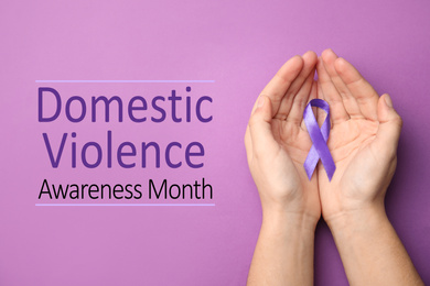 Image of Woman holding purple ribbon on lilac background, top view. Symbol of Domestic Violence Awareness