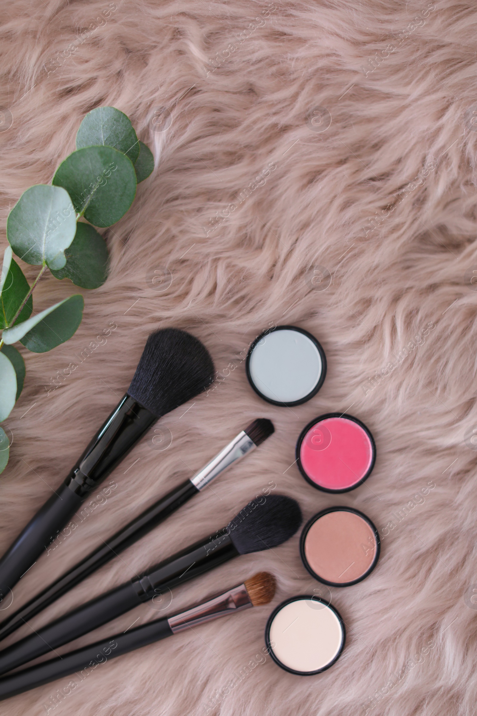 Photo of Flat lay composition with makeup brushes and cosmetic products on faux fur