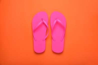 Photo of Stylish pink flip flops on orange background, top view