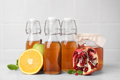 Photo of Tasty kombucha, fresh fruits and mint on white table