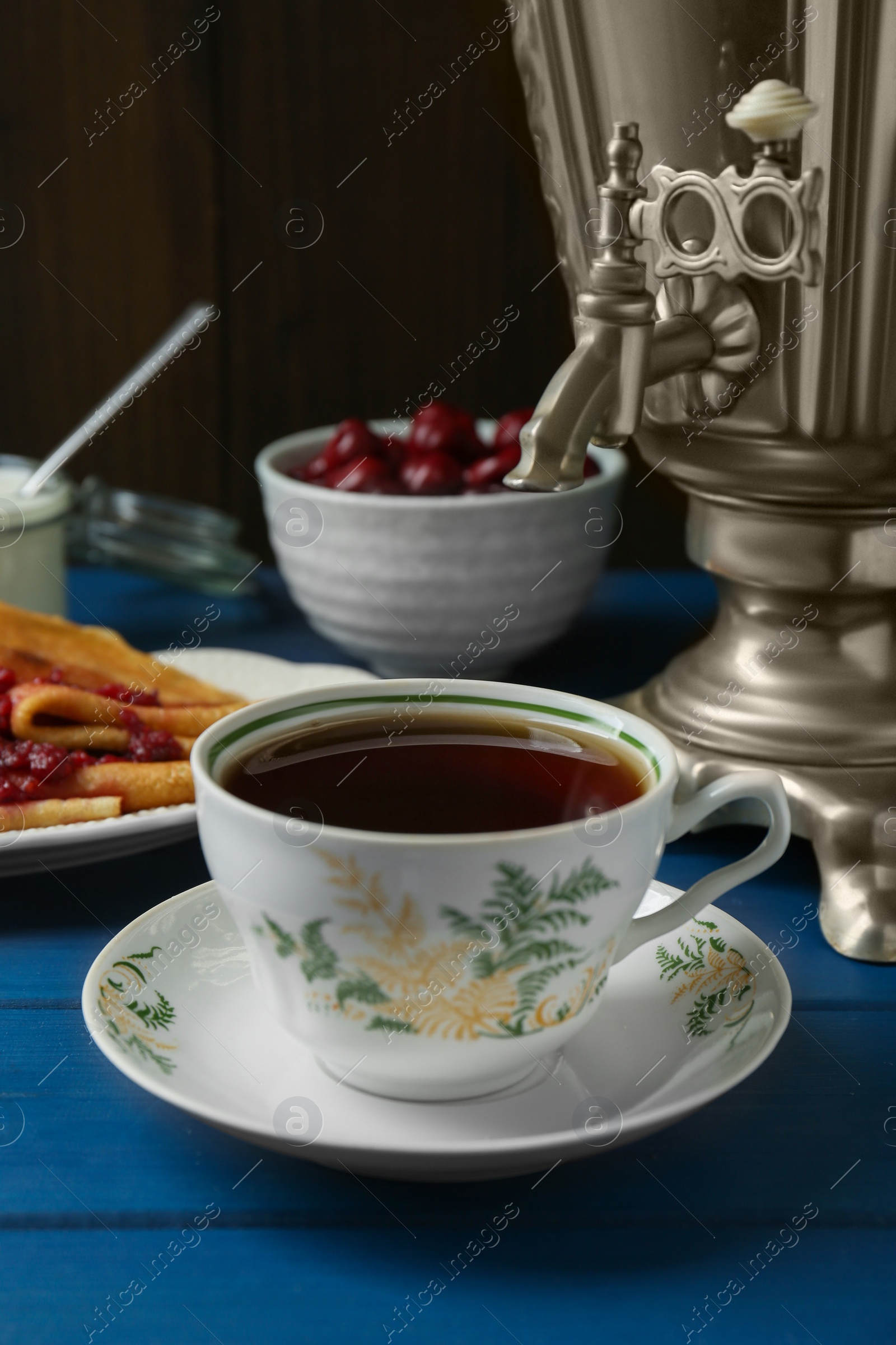 Photo of Aromatic tea, traditional Russian samovar and treats on light blue wooden table