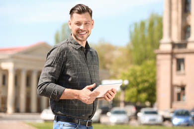 Portrait of young man with tablet outdoors