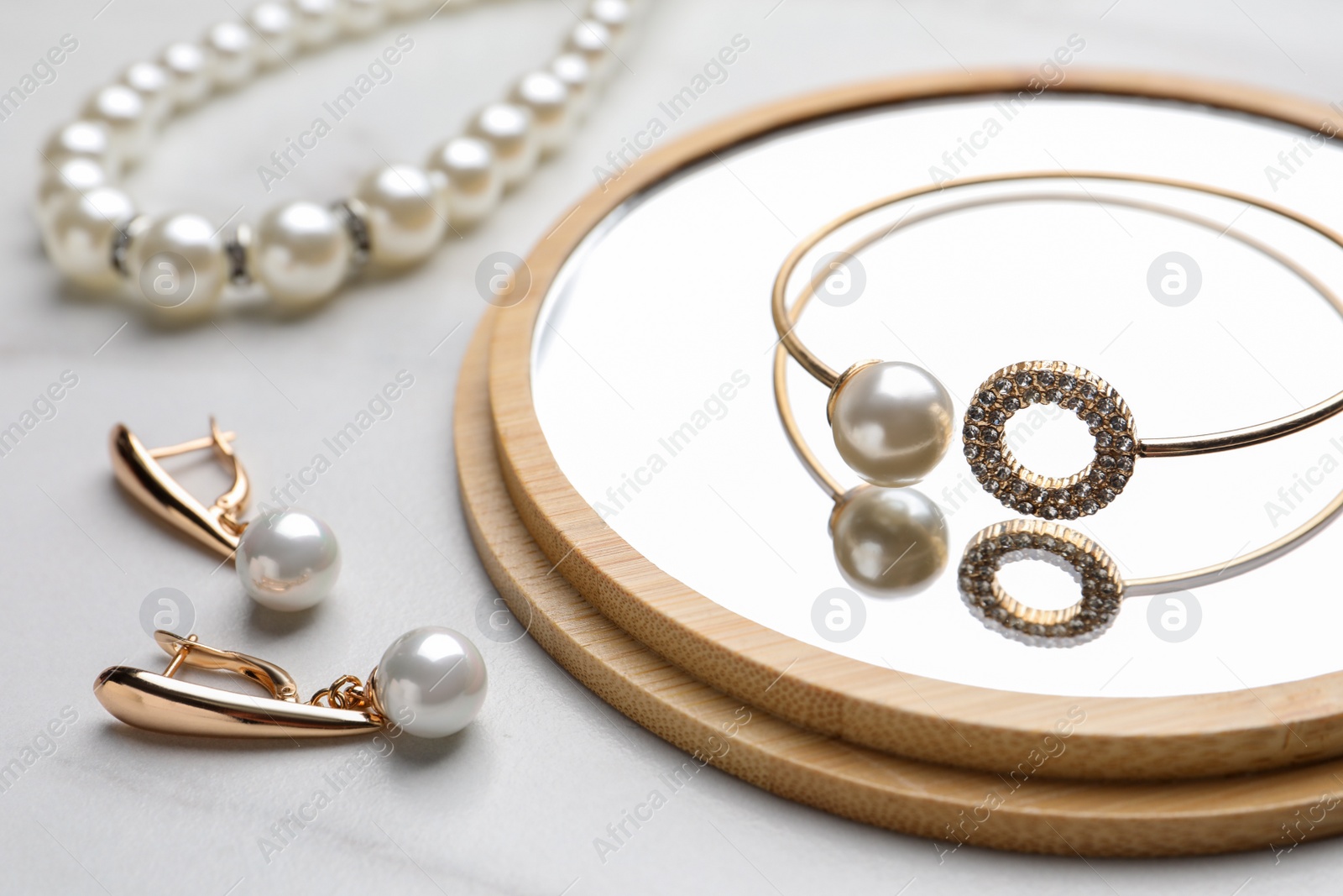 Photo of Elegant necklace, bracelet and earrings with pearls on white marble table, closeup