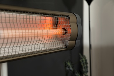 Photo of Modern electric infrared heater in room interior, closeup