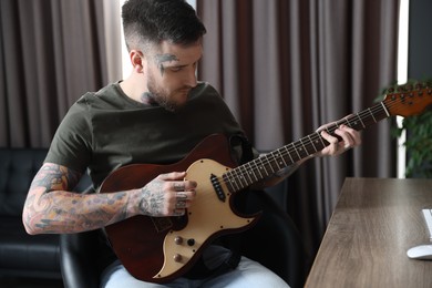Photo of Handsome hipster man playing guitar in room
