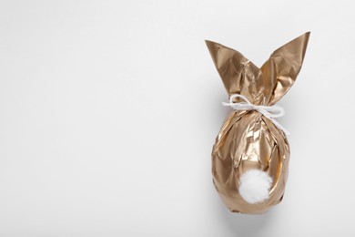 Photo of Easter bunny made of shiny gold paper and egg on white background, top view. Space for text