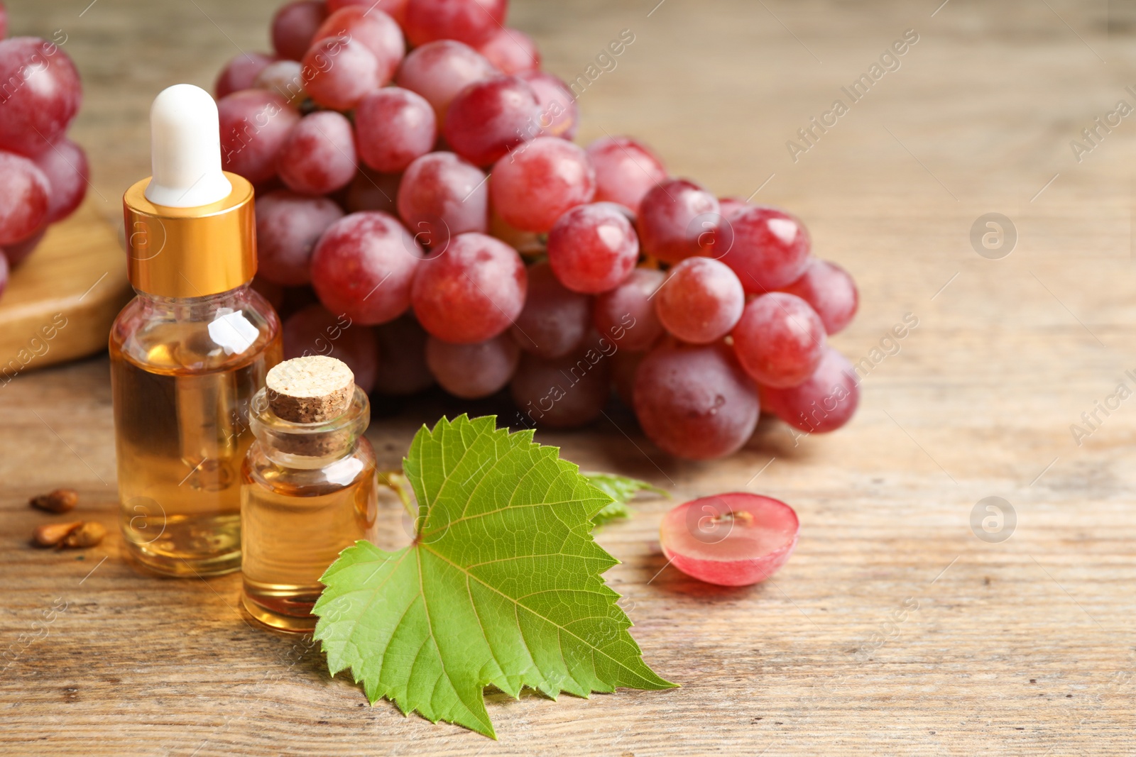 Photo of Natural grape seed oil and fresh berries on wooden table, space for text. Organic cosmetic