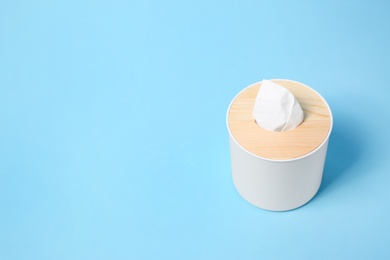 Photo of Holder with paper tissues on light blue background. Space for text