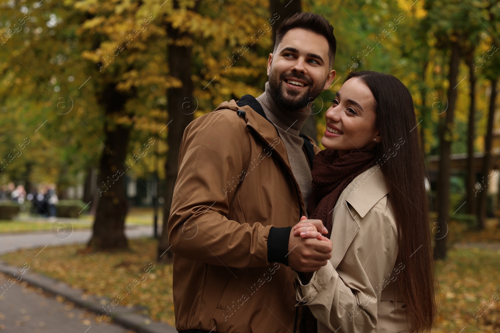 Photo of Romantic young couple spending time together in autumn park, space for text