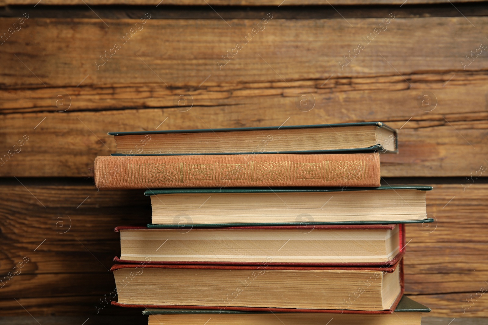 Photo of Collection of different books on table against wooden background