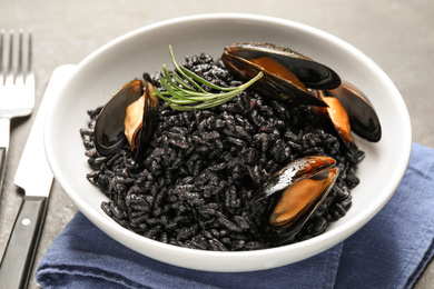 Delicious black risotto with seafood in bowl on table, closeup