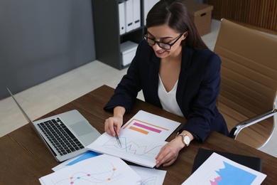 Photo of Beautiful businesswoman working with documents at table in office