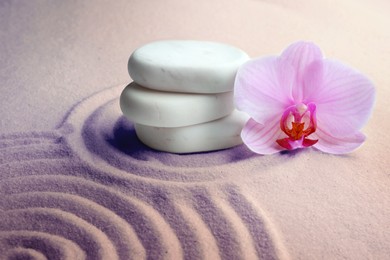 Image of Stack of white stones and beautiful flower on sand with pattern. Zen, meditation, harmony