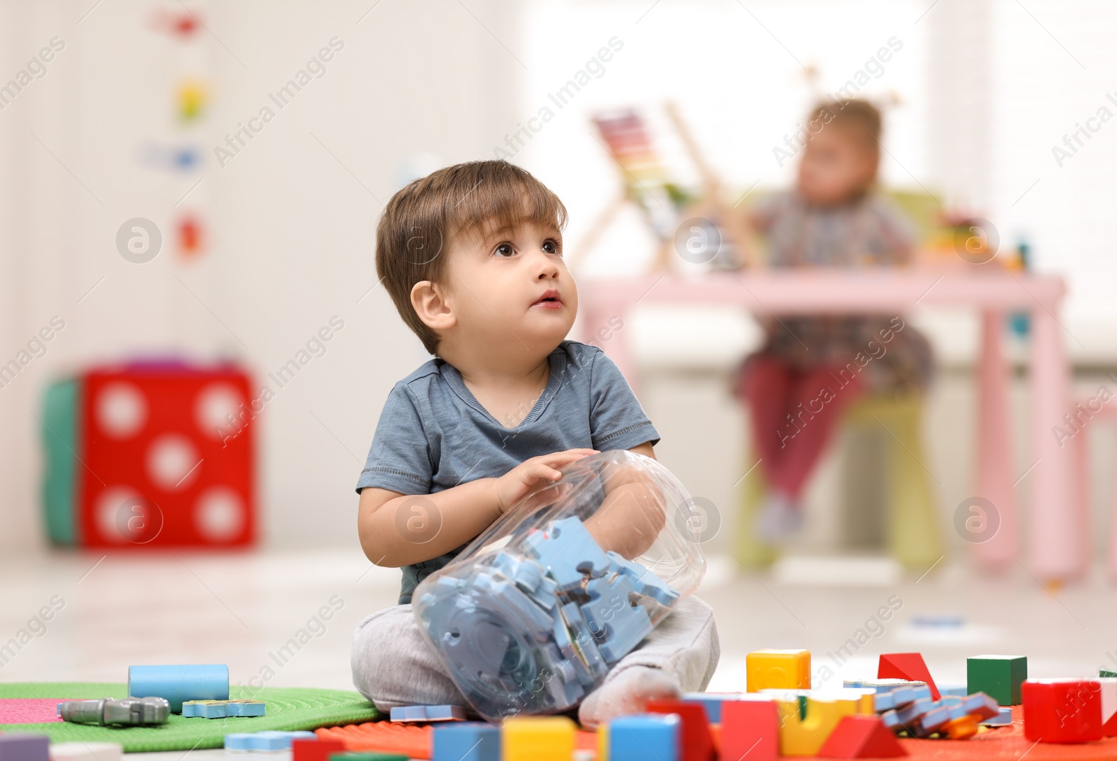 Photo of Cute little child playing with jigsaw puzzles on floor at home