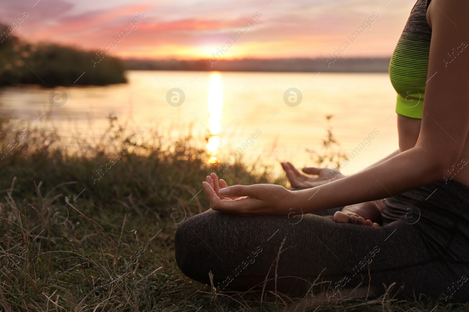 Photo of Woman meditating near river at sunset, closeup. Space for text