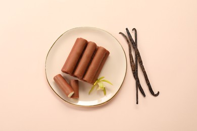 Photo of Glazed curd cheese bars, vanilla pods and flower on light pink background, top view