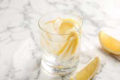 Photo of Soda water with lemon slices and ice cubes on white marble table