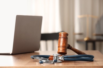 Law concept. Gavel, laptop and stethoscope on wooden table