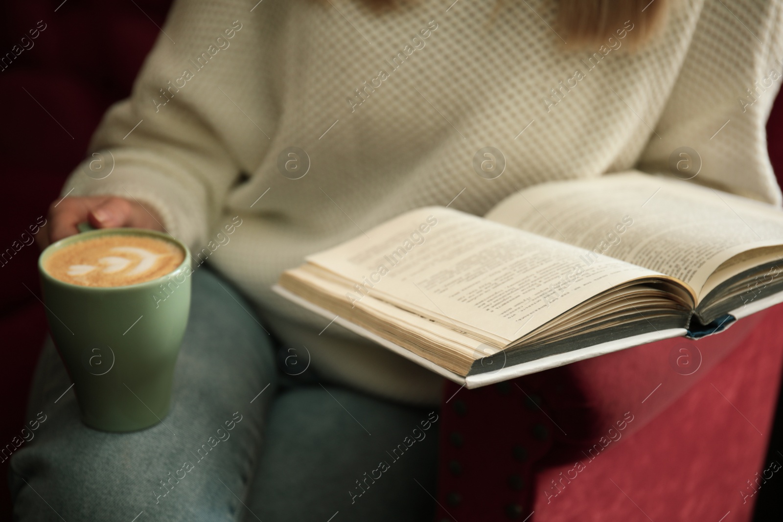 Photo of Woman with cup of coffee reading book indoors, closeup