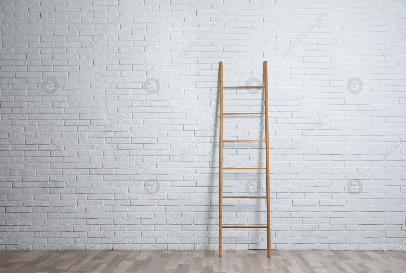 Photo of Modern wooden ladder near white brick wall