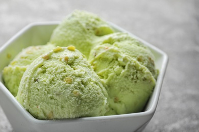 Photo of Delicious pistachio ice cream in bowl on grey table