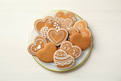 Photo of Tasty heart shaped gingerbread cookies on white wooden table, top view