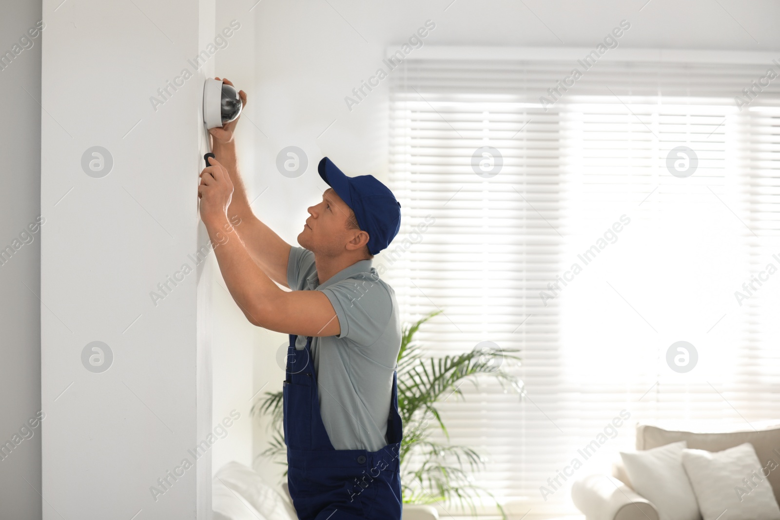 Photo of Technician installing CCTV camera on wall indoors