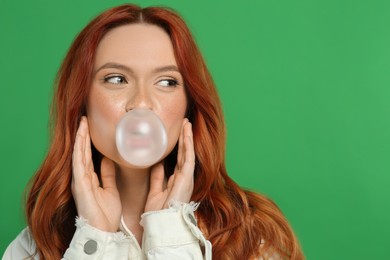 Photo of Beautiful woman blowing bubble gum on green background. Space for text