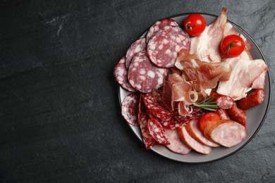 Photo of Different types of sausages with tomatoes served on black table, flat lay. Space for text