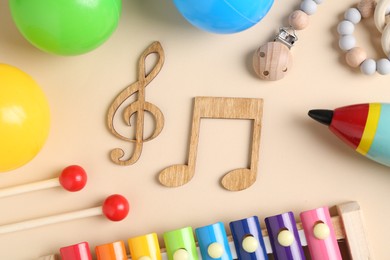 Baby song concept. Wooden notes, kids xylophone and toys on beige background, flat lay