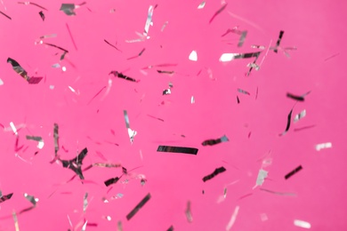 Photo of Shiny silver confetti falling down on pink background