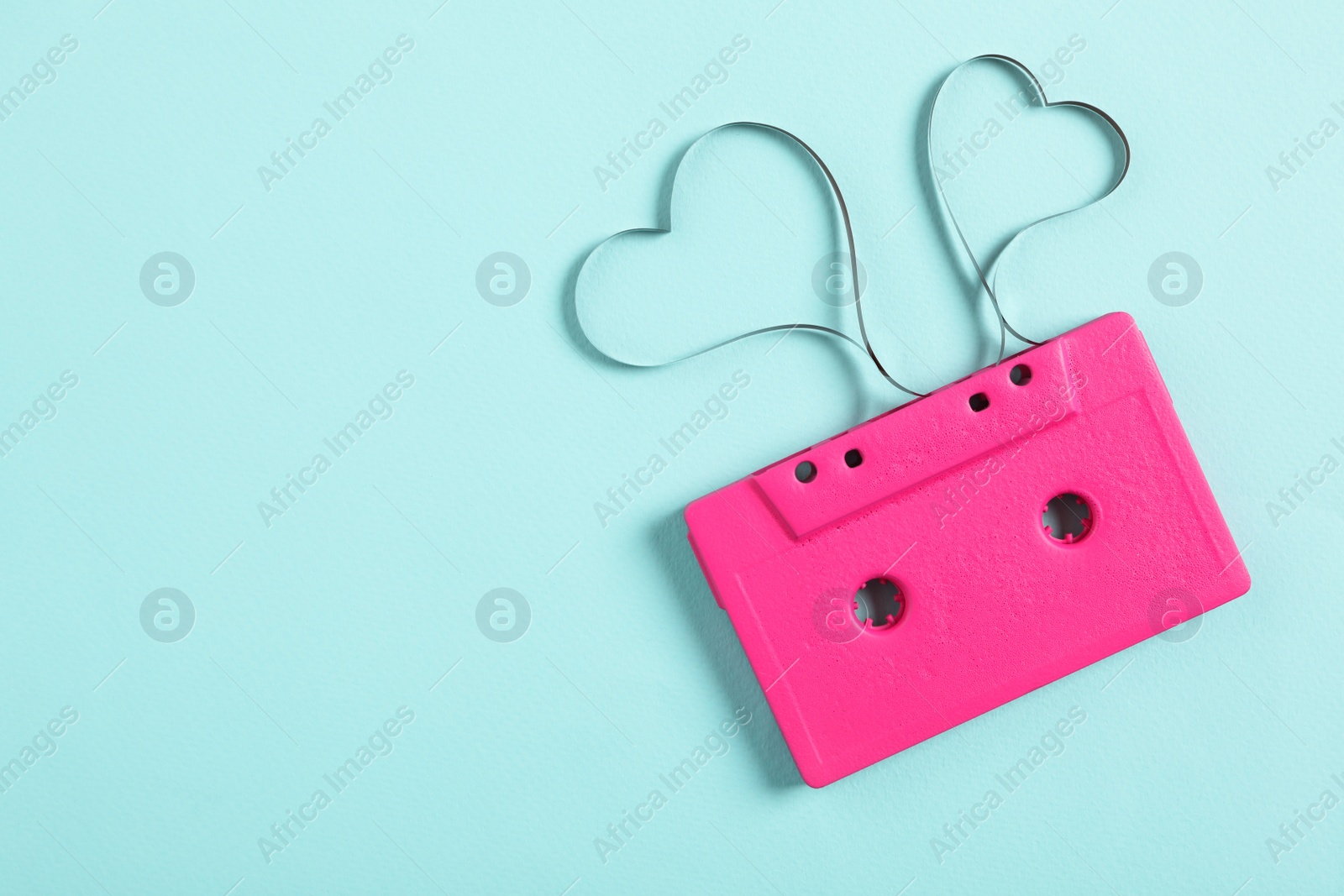 Photo of Top view of music cassette and hearts made with tape on turquoise background, space for text. Listening love song