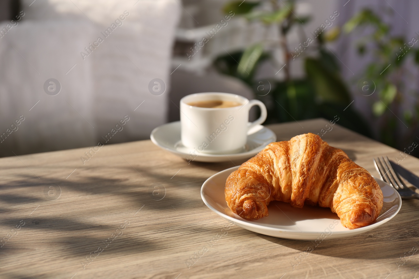 Photo of Delicious fresh croissant served with coffee on wooden table. Space for text