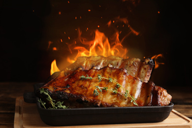 Image of Tasty grilled ribs and flame on wooden board