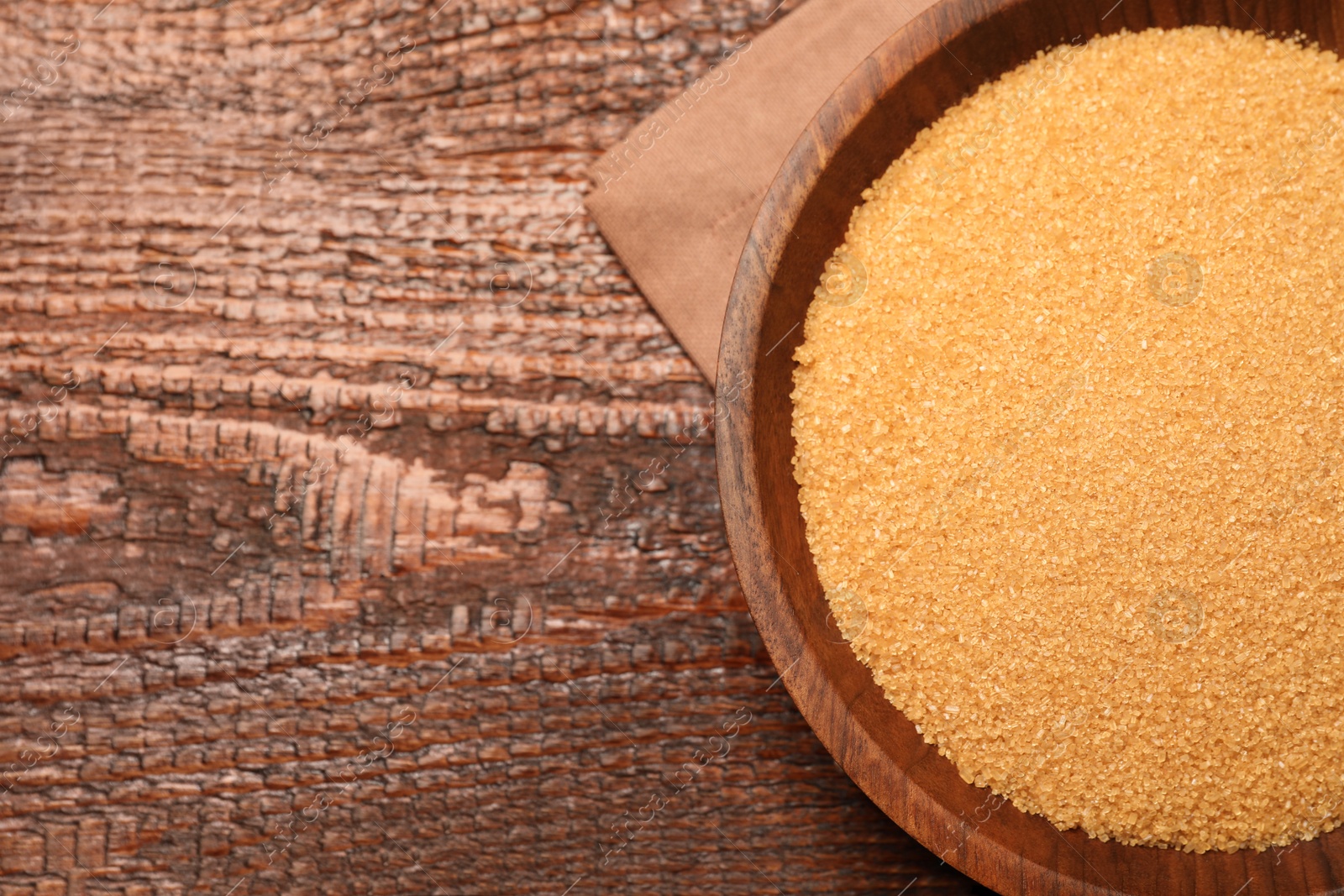 Photo of Brown sugar in bowl on wooden table, top view. Space for text