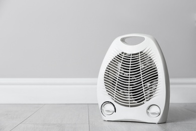 Photo of Modern electric fan heater on floor in room, space for text