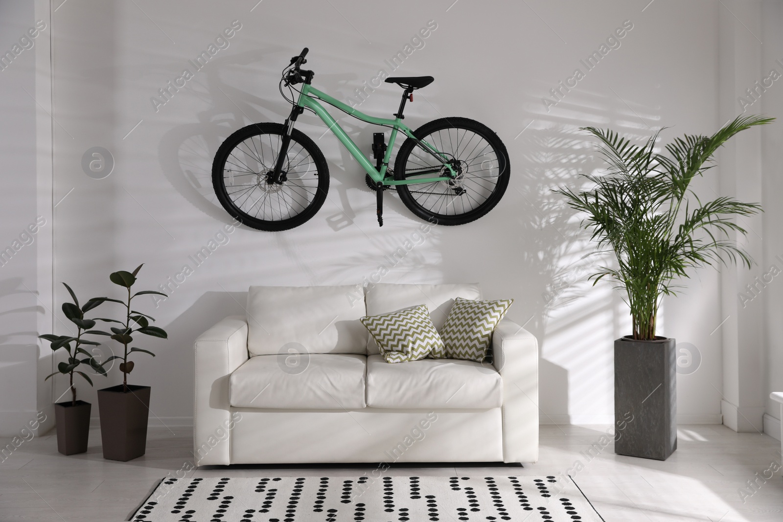 Photo of Stylish living room interior with white sofa and green bicycle